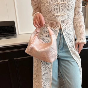 Detail of pink jacquard dumpling bag with elegant beaded tassel and leather handle