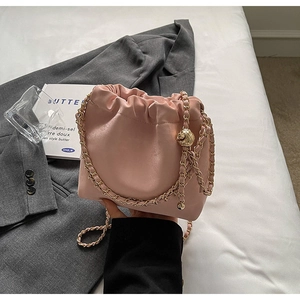 Detail of pink drawstring bucket bag with gold chain strap and adjustable ball buckle