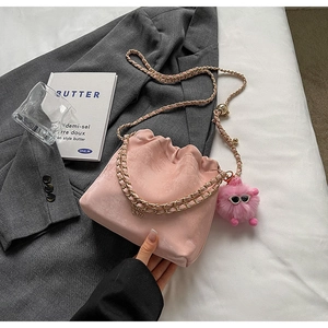Detailed view of pink drawstring bucket bag with gold chain strap and plush ball charm