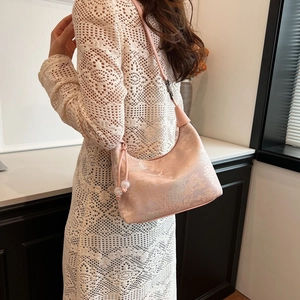 Close-up of pink jacquard hobo bag with landscape patterns on white crochet dress