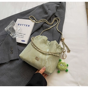 Close-up of light green pleated bucket bag with marble texture and monster charm