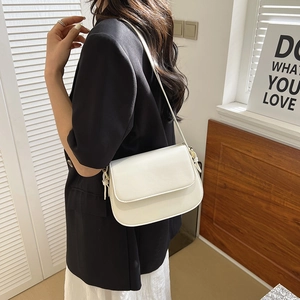 Minimalistische witte lederen crossbodytas gedragen door model in warme setting