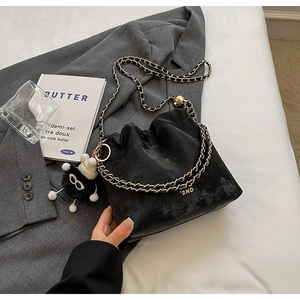 Detail of black suede bucket bag featuring gold '2ND' logo and fuzzy monster charm