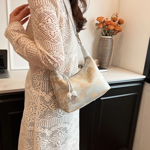 Detail of light blue jacquard dumpling bag with gold patterns and pearl charm