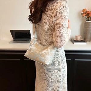 Detailed view of white and gold silk brocade shoulder bag with floral embroidery texture