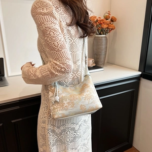Detail of elegant Chinese style dumpling bag with gold landscape art and pearl tassels