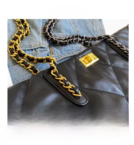 Close-up of black quilted leather texture and golden metal chain strap on a tote bag