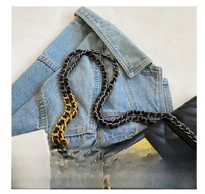Detail of black quilted leather bag with two-tone chain strap and gold twist lock