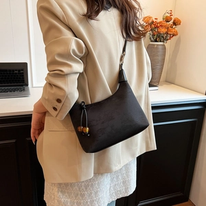 Detail of black faux leather crossbody bag with amber beads and subtle embossed texture
