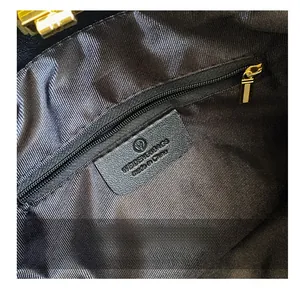 Detail of the dark twill lining with golden zipper pocket and leather brand logo patch