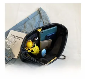 Spacious interior of black quilted tote bag holding umbrella, tablet, and wallet