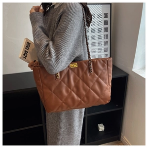 Brown quilted tote bag with gold metal twist lock and chain strap on a female model