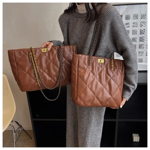 Detailed view of brown quilted leather tote bag featuring gold chain strap and metal lock