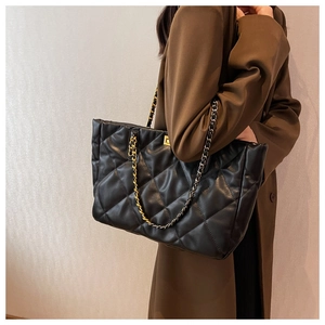 Detail of black quilted tote bag with unique gold and silver dual-tone chain straps