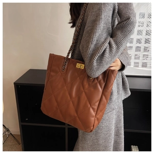 Close-up of brown quilted tote bag showing classic rhombus pattern and gold chain strap