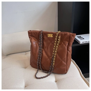 Detailed view of the brown quilted tote bag with metallic chain and turn-lock closure