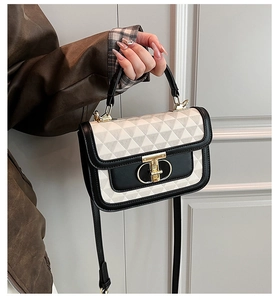 Detail of two-tone contrast bag featuring a geometric texture and golden twist lock