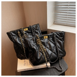 Detail of black quilted leather tote bag with gold chain strap and turn-lock closure