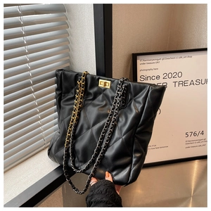 Detail of black quilted tote bag showing leather texture and gold chain strap