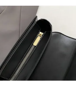 Detailed close-up of smooth gold metal zipper on premium black leather crossbody bag