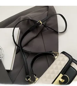 Detail of geometric triangle embossed pattern and gold clasp on cream crossbody bag