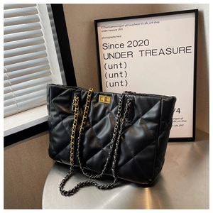 Macro shot of black quilted tote bag with dual-tone metal chains and golden twist-lock closure