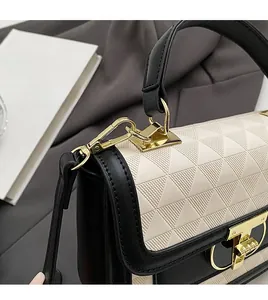 Detail of contrast stitch handbag featuring gold metal hardware and embossed texture