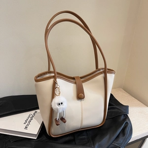 Fashionable cream white bucket tote bag with brown trim and cute monster pom pom charm