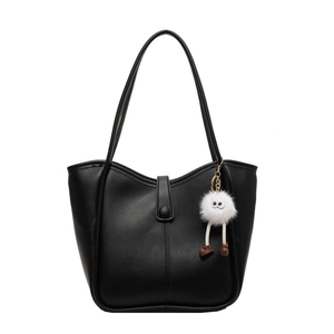 Black leather tote bucket bag with dual handles and cute plush monster charm accessory