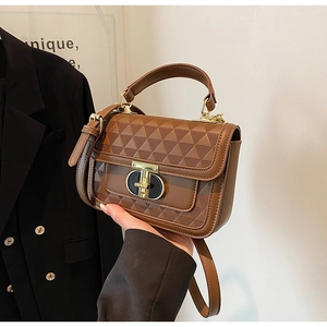 Detail of brown handbag showing geometric triangle pattern and gold T-lock hardware