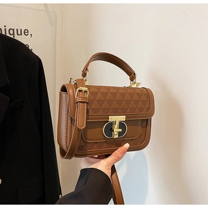 Detailed close-up of brown PU leather bag featuring 3D triangle texture and gold twist lock