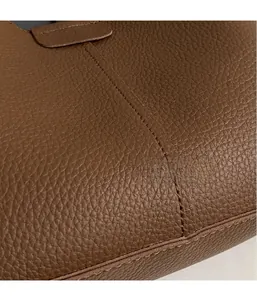 Close-up of brown litchi pattern leather texture and neat stitching on a bucket bag