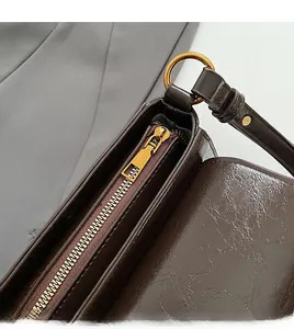 Detail of smooth gold zipper and vintage dark brown waxed leather on shoulder bag