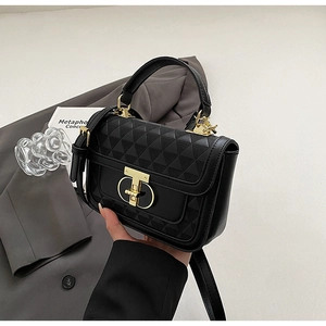 Close-up of black crossbody bag with geometric triangle texture and golden T-clasp