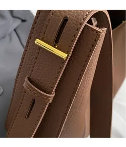 Macro shot of gold metal buckle and brown pebble grain leather stitching detail