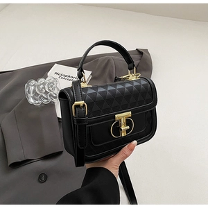 Detail of black leather handbag with triangle quilting and golden T-shaped metal lock