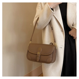 Detail of dark brown lychee leather underarm bag with gold hardware and buckle flap