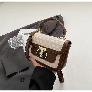 Detail of elegant cream square handbag with geometric texture and golden T-lock