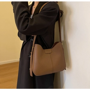 Detail view of brown lychee texture leather shoulder bag shown on model for size
