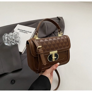 Detail of dark brown leather handbag with geometric triangle texture and gold hardware