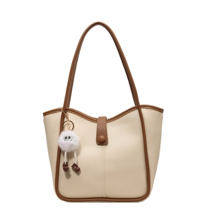 Grande borsa tote beige con manici marroni e ciondolo in peluche su sfondo bianco