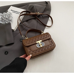 Detail of dark brown leather handbag with geometric patterns and T-shaped metal lock