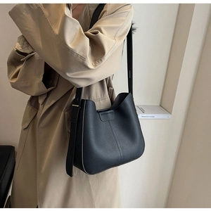 Close-up of black lychee grain leather bucket bag with wavy edge and buckle detail