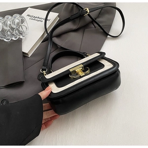 Detail of minimalist quilted crossbody bag featuring contrast stitching and gold metal lock