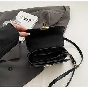 Detail view of the black crossbody bag with multiple interior compartments and gold lock