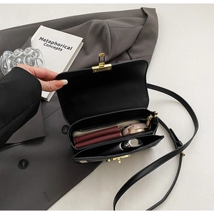 Internal view of black leather crossbody bag showing dual compartments and gold zipper pocket
