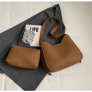 Detail of a brown lychee-grain leather tote bag set on a dark blazer background