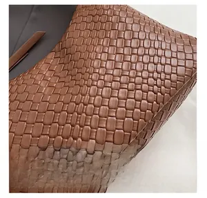 Dettaglio macro della trama in pelle intrecciata premium su una borsa a secchiello marrone
