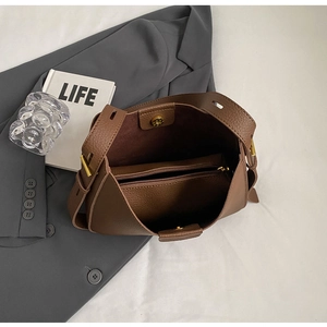 Detailed view of brown lychee grain leather handbag with gold hardware and interior compartments