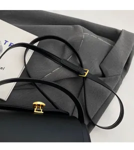 Detail of matte black leather bag with gold buckle and adjustable long shoulder strap